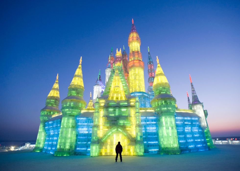 Las esculturas del Festival de Hielo y Nieve de Harbin (China) se iluminan al atardecer con luces de colores. / IAIN MASTERTON